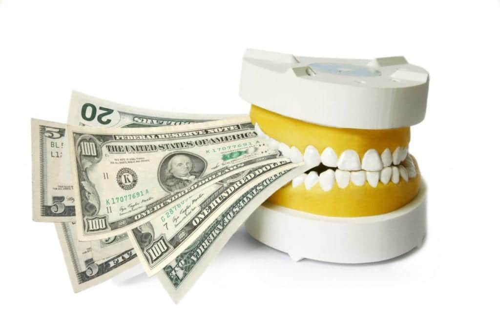 Set of false teeth clenching down on assorted US dollar bills