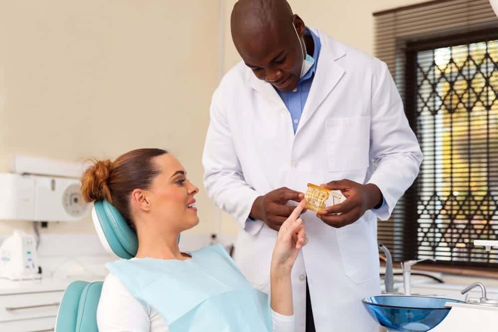 male dentist showing a model of a set of teeth to female patient