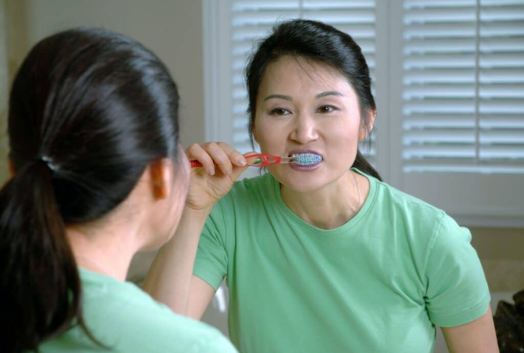 middle-aged woman brushing her teeth