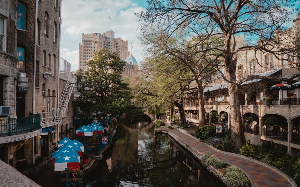 picture of san antonio riverwalk with city buildings in background for article about the cost of dental implants in san antonio texas